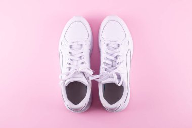 Pair of trendy white sneakers on light pink background, flat lay. Space for text