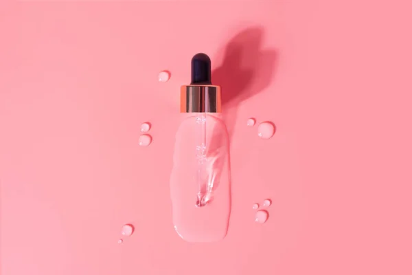 Luxury golden pipette drops of serum moisturized bottle on pink background. Essence transparent hyaluronic acid