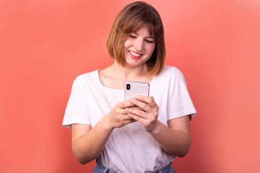 Close-up portrait of her she nice-looking attractive lovely pretty focused cheerful cheerful brown-haired woman using digital device chatting isolated over light pink pastel color background