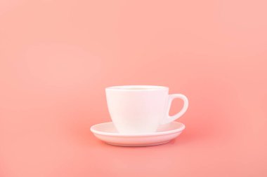 Breakfast and coffee theme:  white empty ceramic coffee cup isolated on a pink background, advertising coffee