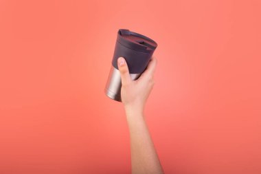 Photo of cup, thermo mug of coffee in hand isolated on pink background. Banner design. Cup of tea