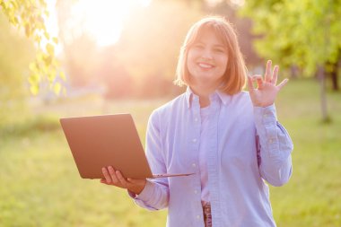 Portrait of attractive amazed cheerful girl agent broker using laptop having fun in green park