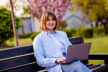 Photo of attractive lady student sit on bench in green park browsing notebook chatting friends do home tasks inspiration nature beauty harmony wear white t-shirt park outdoors