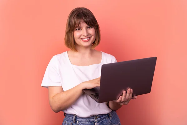 Portrait of attractive amazed cheerful girl agent broker using laptop having fun isolated over pink pastel color background