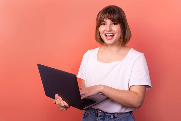 Portrait of attractive amazed cheerful girl agent broker using laptop having fun isolated over pink pastel color background