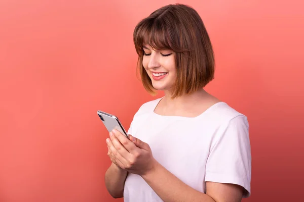 Photo of impressed bob hairdo young lady hold telephone wear white t shirt isolated on pink color background