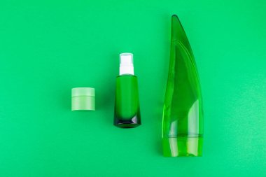 moisturizes serum, jar of cream on green background. Moisturizing beauty product with organic. Body care lotion. Simple empty packaging beauty cosmetics. Mock up, copy space