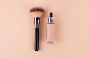 Liquid foundation cream unbranded bottle with makeup brush. Facial correction, liquid concealer, tone, bb, cc cream skincare product on beige background. Feminine cosmetics accessory with copy space