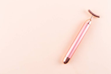 Face massager vibration roller on beige background. Facial massage and beauty concept, relax and spa. Place for text.