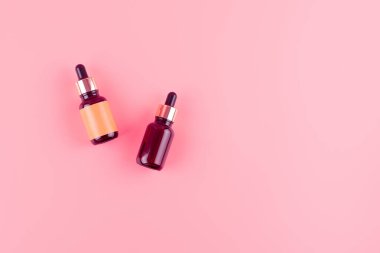 Flatlay brown glass bottles with a pipette on pink background top view. Organic natural essential oil for aromatherapy. Beauty product for body and face skin care. Moisturizing serum.