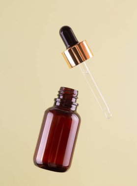 Flying opened brown dropper glass bottle with pipette on green background. Serum, acid, oil. Zero waste. Organic, natural cosmetic. Spa, beauty, skincare product. Levitation in the air concept