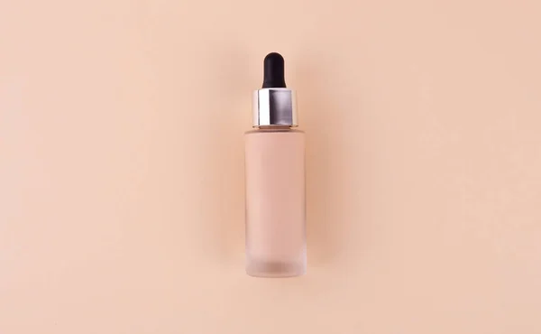 Liquid foundation cream unbranded bottle on a beige background. BB cream for professional make-up, eyedropper for applying to the face. Cosmetic female accessory, fluid. Mock up concept