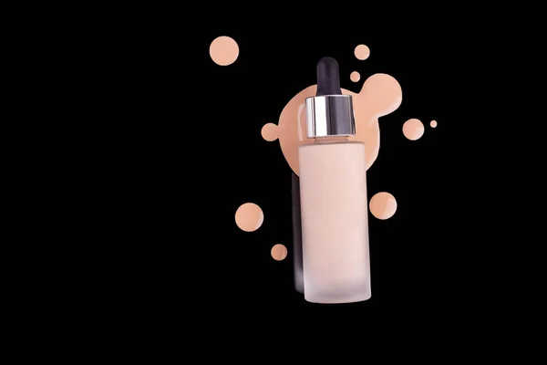 Spilled liquid foundation. Mockup glass bottle of correction cosmetic product with pipette for make up on black background. beauty branding concept