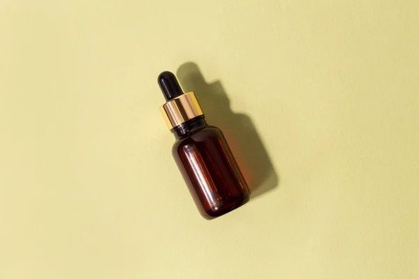 glass brown bottle with pipette with essential oil on a pastel green background top view. Aromatic cosmetic product for skin and hair care Moisturizing beauty product with organic