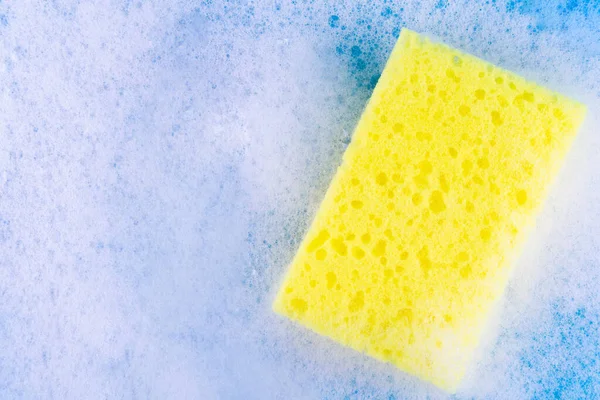 yellow sponge in white bubble foam for dish wash. Washcloth covered in soap. Domestic chores and supplies concept. Sensitive dishwashing detergent. cleaning company concept