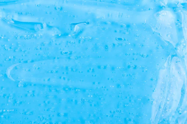 The texture of a liquid transparent gel for face cleansing. Sample of oil serum with bubbles on a blue background. Moisturizing cosmetic beauty product for skincare. Lotion for dry skin care