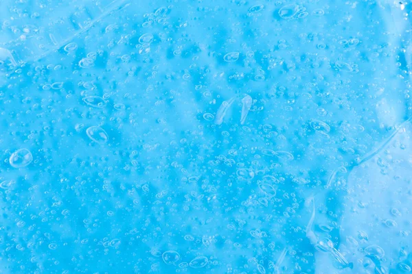 The texture of a liquid transparent gel for face cleansing. Sample of oil serum with bubbles on a blue background. Moisturizing cosmetic beauty product for skincare. Lotion for dry skin care