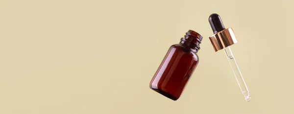 Flying opened brown dropper glass bottle with pipette on green background. Serum, acid, oil. Zero waste. Organic, natural cosmetic. Spa, beauty, skincare product. Levitation in the air concept