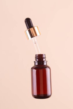 Flying opened brown dropper glass bottle with pipette on beige background. Serum, acid, oil. Zero waste. Organic, natural cosmetic. Spa, beauty, skincare product. Levitation in the air concept