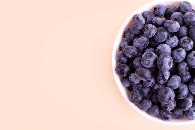 Fresh blueberries in white plate on beige background. Vegan and vegetarian concept. Summer healthy food. Flatlay