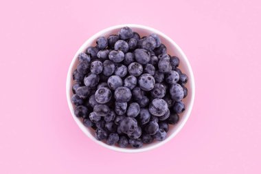 Top view of fresh ripe blueberries in bowl isolated on pink. Healthy, natural fruit. Vegan and vegetarian concept. Summer healthy food. 