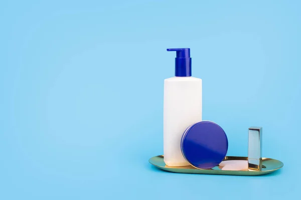 Natural beauty dermatology cosmetic cream white bottle and blue cream jar, skin care on isolated blue background with copyspace. Mockup. Flatlay beauty and spa concept