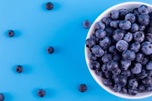Top view of fresh ripe blueberries in bowl isolated on blue. Healthy, natural fruit. Vegan and vegetarian concept. Summer healthy food. 