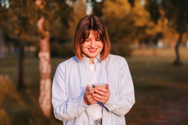 Portrait of cute adorable charming focused woman surfing online receive notifications go walk outside in green park