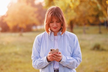 Portrait of cute adorable charming focused woman surfing online receive notifications go walk outside in green park