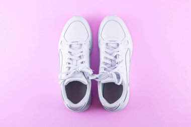 Pair of trendy white sneakers on light pink background, flat lay. Space for text