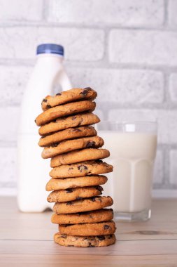 Flatlay an after school snack of chocolate chip cookies and an glass cup of milk, bottle of milk. The cookies with chocolate drops and on a rustic wood kitchen table, with copy space. yummy and tasty
