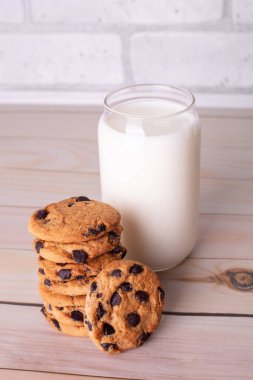 Flatlay an after school snack of chocolate chip cookies and an glass cup of milk. The cookies with chocolate drops and on a rustic wood kitchen table, with copy space. yummy and tasty