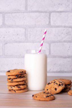 Flatlay an after school snack of chocolate chip cookies and an glass cup of milk. The cookies with chocolate drops and on a rustic wood kitchen table, with copy space. yummy and tasty