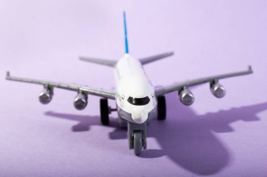 Beyaz model uçağın üst görüntüsü, izole edilmiş mor arka planda uçak oyuncağı. Fotokopi alanı olan düz bir yer. Trip veya seyahat afişi