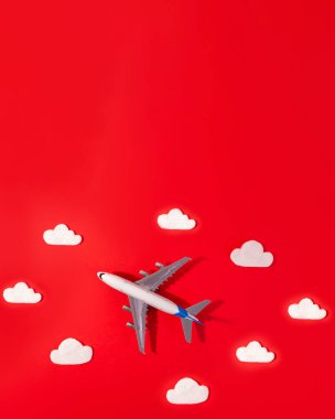 Kırmızı ve fotokopi uzayında uçak ve bulut ile seyahat konseptinin düz dizaynı. Çocuk için küçük uçak modeli oyuncağı