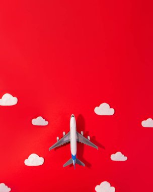 Kırmızı ve fotokopi uzayında uçak ve bulut ile seyahat konseptinin düz dizaynı. Çocuk için küçük uçak modeli oyuncağı