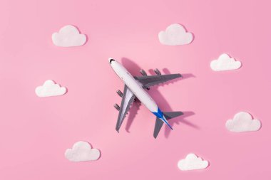 Düz dizayn edilmiş uçak ve bulutlu seyahat konsepti. Pembe arka planda ve fotokopi alanında. Çocuk için küçük uçak modeli oyuncağı