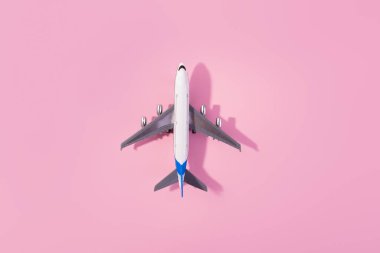 Beyaz model uçağın üst görüntüsü, izole edilmiş pembe arka planda uçak oyuncağı. Fotokopi alanı olan düz bir yer. Trip veya seyahat afişi