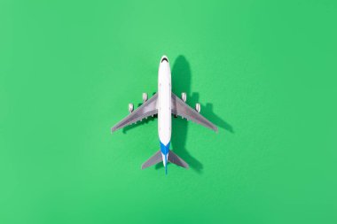 Beyaz model uçağın üst görüntüsü, izole edilmiş yeşil arka planda uçak oyuncağı. Fotokopi alanı olan düz bir yer. Trip veya seyahat afişi