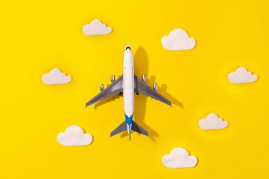 Düz dizayn edilmiş seyahat konsepti, sarı üzerinde bulut ve uçak ve kopyalama uzayı. Çocuk için küçük uçak modeli oyuncağı