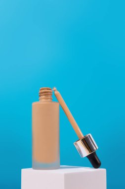 Temelinde sıvı bej krem bulunan beyaz bir kürsüde açıldı. Mükemmel cilt için profesyonel makyaj ürünü. Kadın aksesuarları, temel güzellik ürünleri, astar, kapatıcı.