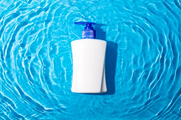 Mock up white tube with cosmetic product for moisturizing in water on blue background. Template for desig