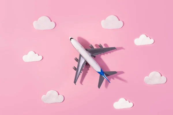 Flat lay design of travel concept with plane and cloud on pink and pink background with copy space. Small airplane model toy for childre