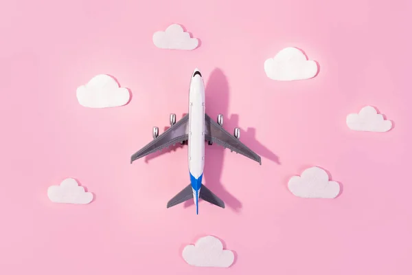 Flat lay design of travel concept with plane and cloud on pink and pink background with copy space. Small airplane model toy for childre