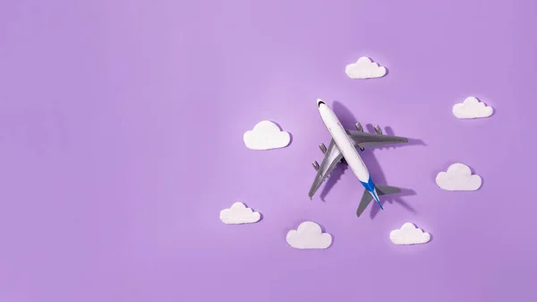 Flat lay design of travel concept with plane and cloud on purple and  copy space. Small airplane model toy for childre