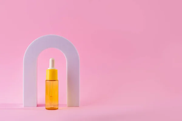 Cosmetic yellow bottle with vitamin c serum in arch. Skin care cosmetic. Hyaluronic acid oil, serum with collagen and peptides