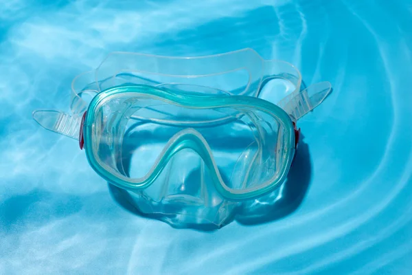 flat lay shot of blue diving mask over turquoise blue background. minimalist photo of dive mask under wate