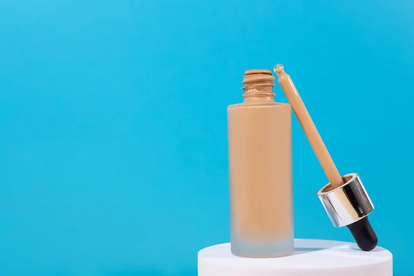 Temelinde sıvı bej krem bulunan beyaz bir kürsüde açıldı. Mükemmel cilt için profesyonel makyaj ürünü. Kadın aksesuarları, temel güzellik ürünleri, astar, kapatıcı.