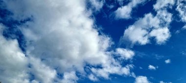 Açık mavi gökyüzünde kabarık bulutlar