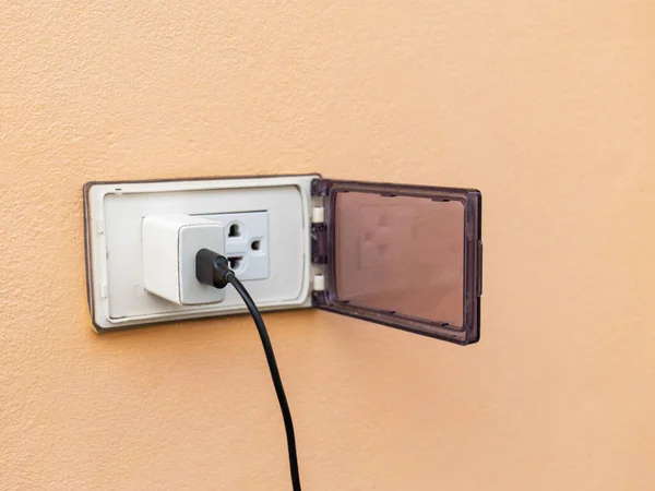 Eski beyaz adaptör. Fişe takılı bir şarj kablosu var. Dış duvar tıkaçlarıyla, tehlikeyi önlemek için kullanılmadığında kapanan bir kapak var. Coppy alanı var..